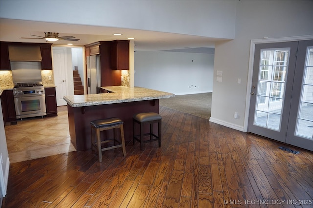 1207 E 21st Pl, Tulsa, OK 74114 - kitchen with stainless steel appliances, dark wood finished floors, a breakfast bar area, ceiling fan, and light stone counters