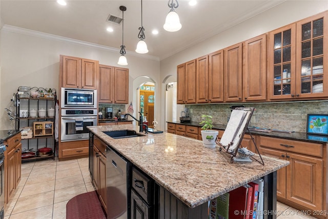 13559 E 463rd Rd, Claremore, OK 74017 - kitchen featuring stainless steel appliances, arched walkways, an island with sink, tasteful backsplash, and light stone countertops