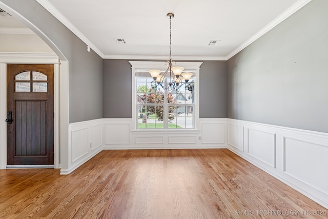 3604 W 109th St S, Jenks, OK 74037 - unfurnished dining area featuring arched walkways, a chandelier, light wood-type flooring, a wainscoted wall, and ornamental molding