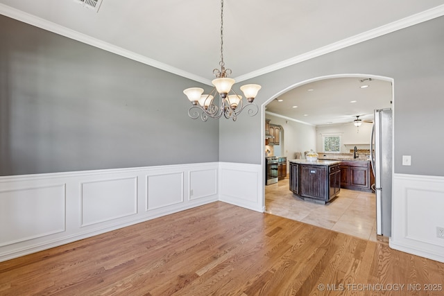 3604 W 109th St S, Jenks, OK 74037 - unfurnished dining area featuring arched walkways, light wood-type flooring, a wainscoted wall, crown molding, and recessed lighting