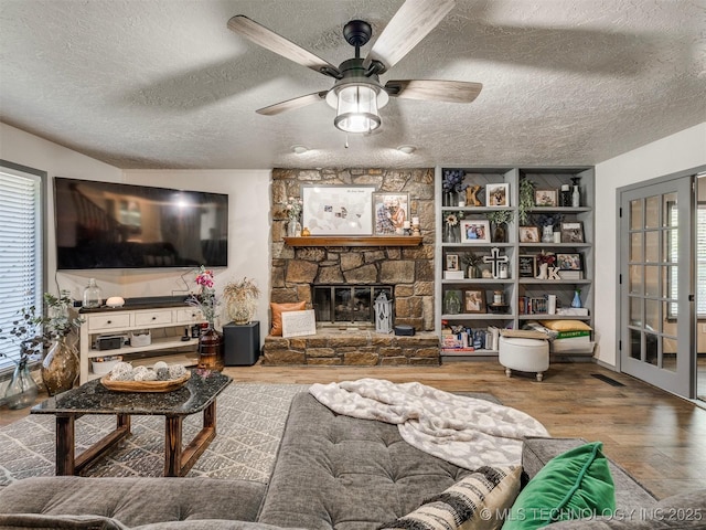6708 S 5th St, Broken Arrow, OK 74011 - living room featuring a textured ceiling, wood finished floors, a ceiling fan, and a fireplace