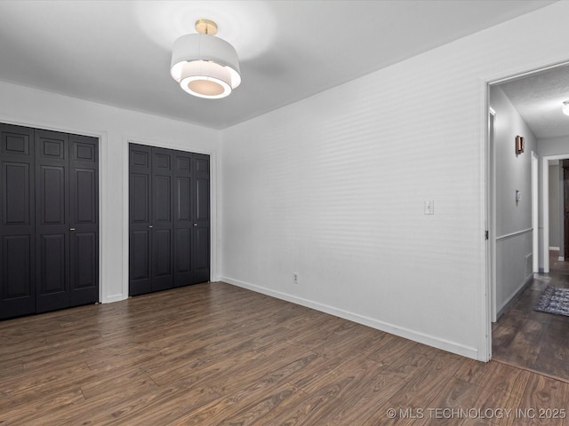 6725 Dorsett Dr, Bartlesville, OK 74006 - unfurnished bedroom with dark wood-style flooring and two closets