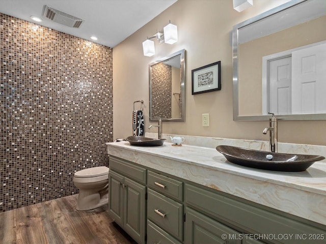 6725 Dorsett Dr, Bartlesville, OK 74006 - full bathroom with double vanity, wood finished floors, tile walls, and recessed lighting