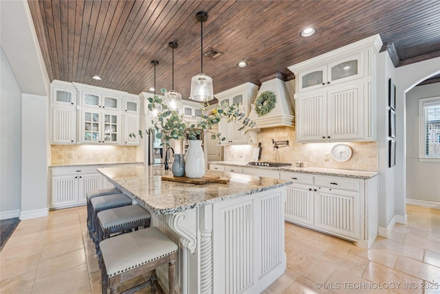 11029 S Kennedy St, Jenks, OK 74037 - kitchen with premium range hood, wood ceiling, decorative backsplash, arched walkways, and an island with sink