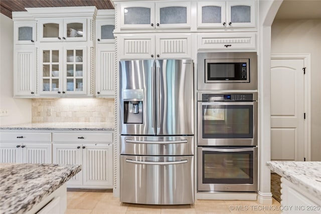 11029 S Kennedy St, Jenks, OK 74037 - kitchen featuring appliances with stainless steel finishes, white cabinets, arched walkways, and backsplash