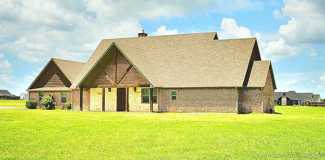 6865 Wilson St, Durant, OK 74701 - tudor home featuring a front lawn, a chimney, roof with shingles, and brick siding