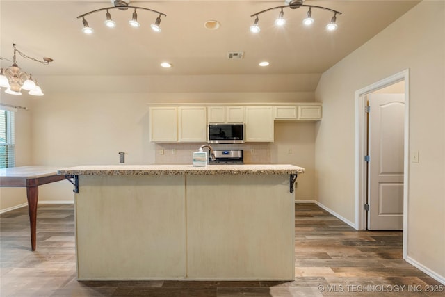 12522 S Cedar Ave, Jenks, OK 74037 - kitchen with appliances with stainless steel finishes, an island with sink, a chandelier, tasteful backsplash, and dark wood-style flooring