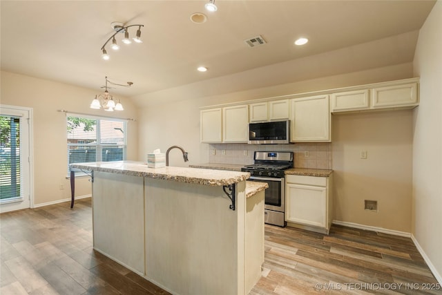 12522 S Cedar Ave, Jenks, OK 74037 - kitchen with appliances with stainless steel finishes, a chandelier, light stone countertops, wood finished floors, and tasteful backsplash