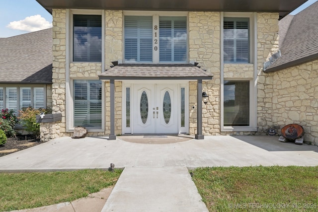 8120 E 112th St, Owasso, OK 74055 - doorway to property featuring stone siding and roof with shingles