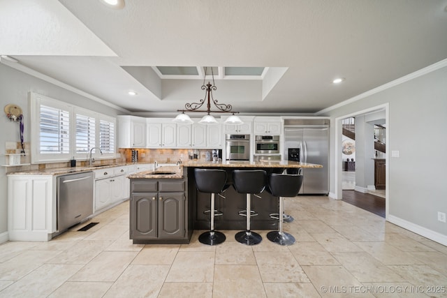 8120 E 112th St, Owasso, OK 74055 - kitchen featuring appliances with stainless steel finishes, crown molding, white cabinetry, an island with sink, and light stone counters