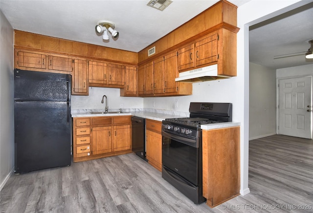20529 E 4th St, Tulsa, OK 74108 - kitchen with black appliances, under cabinet range hood, light wood-style flooring, and light countertops
