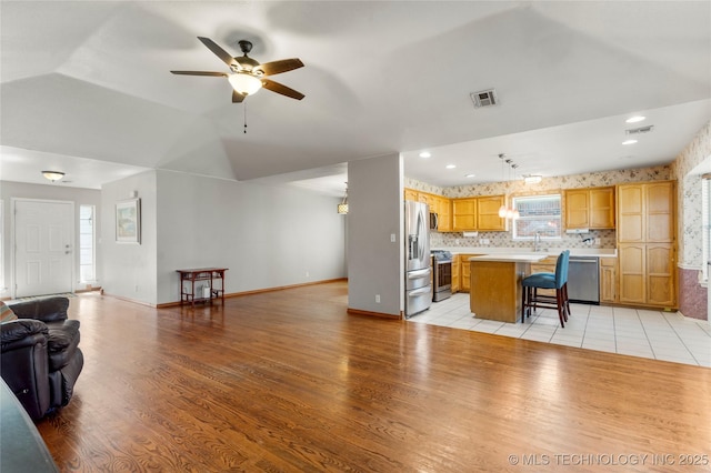 3220 N 3rd Pl, Broken Arrow, OK 74012 - kitchen with open floor plan, stainless steel appliances, light countertops, a breakfast bar area, and light wood finished floors