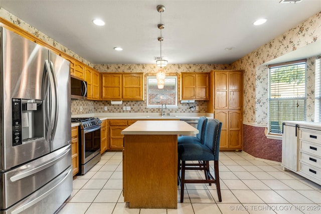 3220 N 3rd Pl, Broken Arrow, OK 74012 - kitchen featuring appliances with stainless steel finishes, wallpapered walls, light countertops, a kitchen bar, and a kitchen island