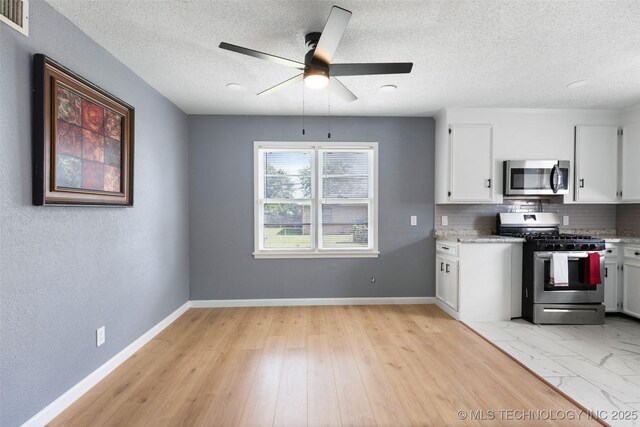 10942 E 4th Pl N, Tulsa, OK 74128 - kitchen featuring appliances with stainless steel finishes, a ceiling fan, white cabinets, tasteful backsplash, and a textured ceiling