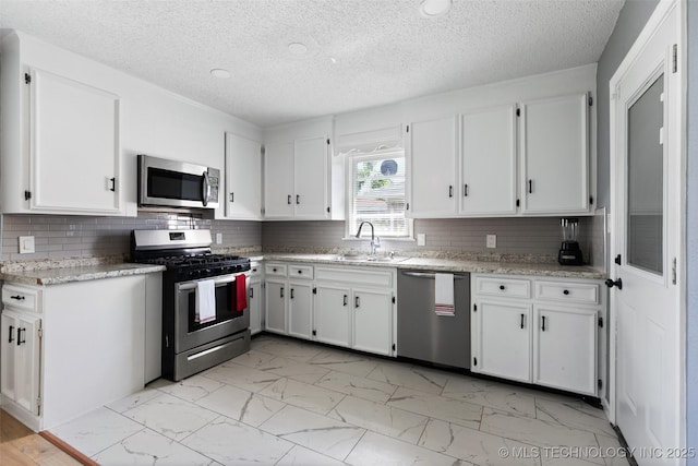 10942 E 4th Pl N, Tulsa, OK 74128 - kitchen with stainless steel appliances, light marble finish flooring, white cabinets, a textured ceiling, and decorative backsplash