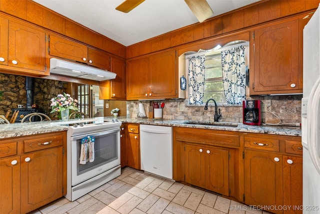 3811 Broadway Ct, Ada, OK 74820 - kitchen with white appliances, under cabinet range hood, backsplash, a wood stove, and brown cabinetry