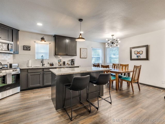11 Port Duncan, Afton, OK 74331 - kitchen with stainless steel appliances, plenty of natural light, decorative backsplash, a kitchen breakfast bar, and a textured ceiling