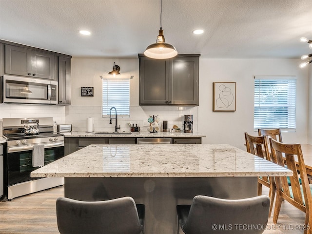 11 Port Duncan, Afton, OK 74331 - kitchen featuring appliances with stainless steel finishes, a kitchen bar, decorative backsplash, light wood finished floors, and a textured ceiling