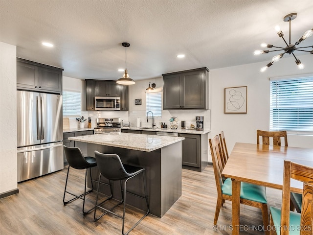 11 Port Duncan, Afton, OK 74331 - kitchen featuring appliances with stainless steel finishes, light stone countertops, a kitchen island, a chandelier, and decorative backsplash