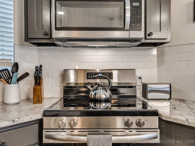 11 Port Duncan, Afton, OK 74331 - kitchen view of appliances with stainless steel finishes, tasteful backsplash, light stone counters, and gray cabinets