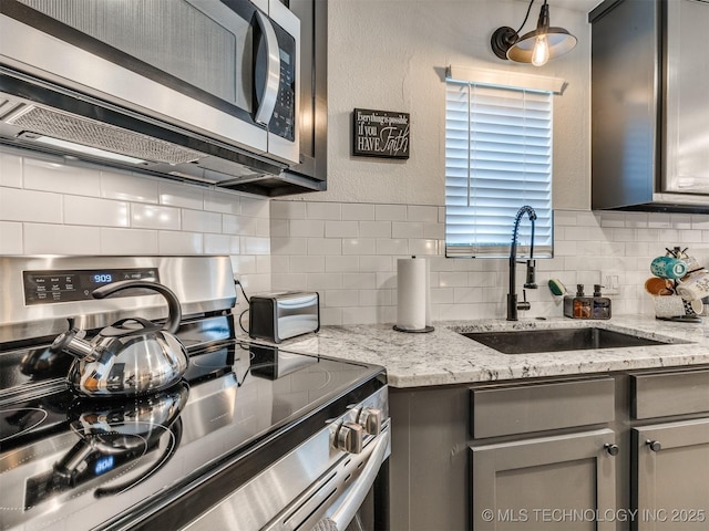 11 Port Duncan, Afton, OK 74331 - kitchen featuring appliances with stainless steel finishes, gray cabinets, backsplash, and light stone counters