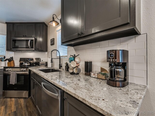 11 Port Duncan, Afton, OK 74331 - kitchen featuring appliances with stainless steel finishes, decorative backsplash, dark wood finished floors, a textured wall, and light stone counters