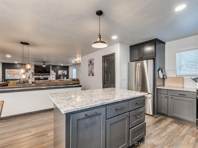 11 Port Duncan, Afton, OK 74331 - kitchen featuring freestanding refrigerator, wood finished floors, gray cabinetry, light stone countertops, and pendant lighting