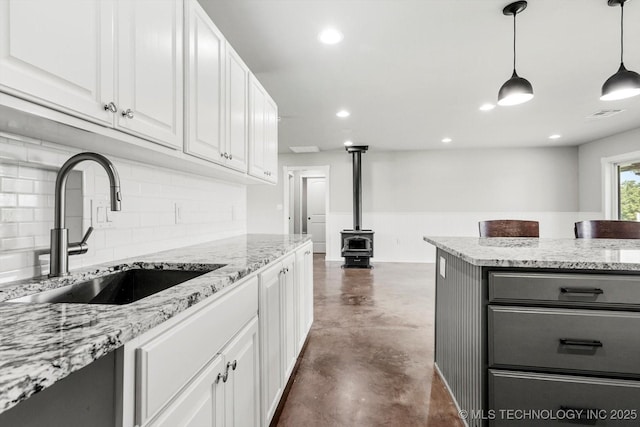 36619 W 141st St S, Bristow, OK 74010 - kitchen featuring finished concrete floors, a wood stove, decorative backsplash, white cabinetry, and recessed lighting