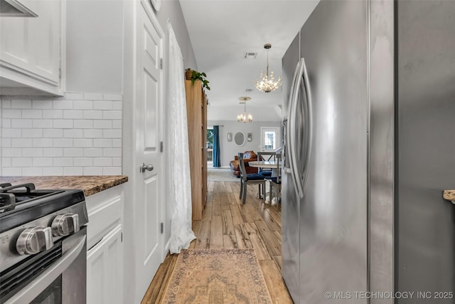 19912 E 36th St S, Broken Arrow, OK 74014 - kitchen featuring stainless steel appliances, white cabinets, backsplash, a chandelier, and light wood finished floors