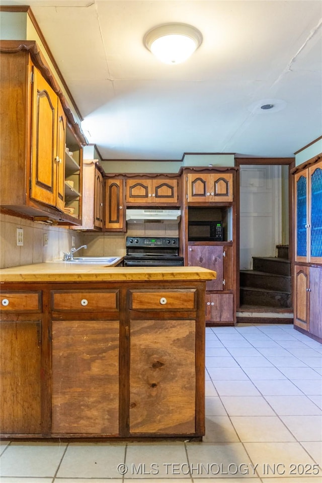 519 N 15th St, Muskogee, OK 74401 - kitchen featuring black appliances, light tile patterned floors, under cabinet range hood, brown cabinetry, and open shelves