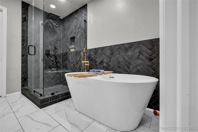 14900 E 88th St N, Owasso, OK 74055 - bathroom with marble finish flooring, tile walls, a freestanding tub, a stall shower, and recessed lighting