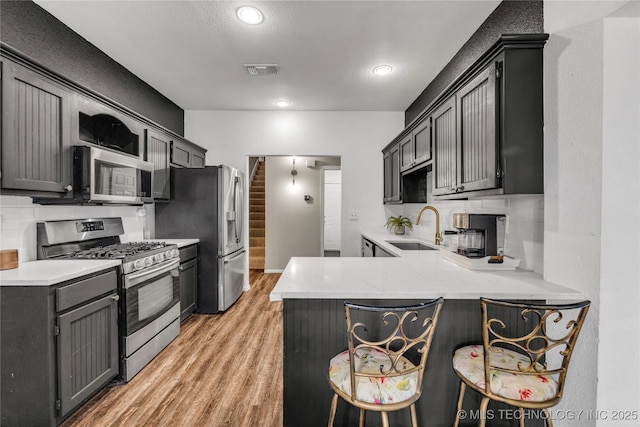 14900 E 88th St N, Owasso, OK 74055 - kitchen with stainless steel appliances, a peninsula, light wood-style floors, light countertops, and a breakfast bar