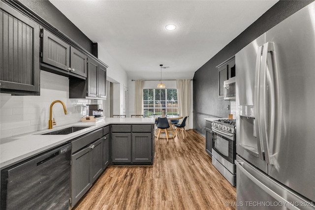 14900 E 88th St N, Owasso, OK 74055 - kitchen with appliances with stainless steel finishes, light wood finished floors, a peninsula, tasteful backsplash, and light countertops