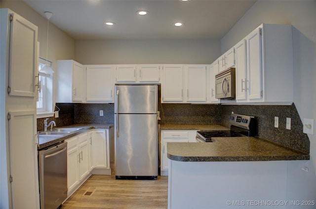1420 S Frisco Ave Unit 6, Tulsa, OK 74119 - kitchen with appliances with stainless steel finishes, dark countertops, light wood-type flooring, a peninsula, and white cabinetry