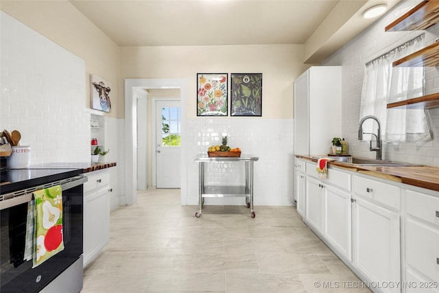212 S Phoenix Ave, Tulsa, OK 74127 - kitchen with stainless steel electric range, wooden counters, white cabinetry, open shelves, and decorative backsplash