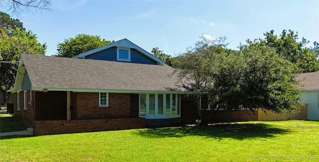 610 W Delaware St, Tahlequah, OK 74464 - back of house featuring brick siding, a shingled roof, and a lawn