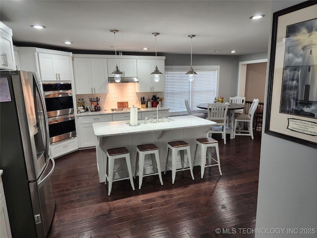 610 W Delaware St, Tahlequah, OK 74464 - kitchen with appliances with stainless steel finishes, range hood, a kitchen bar, recessed lighting, and white cabinetry