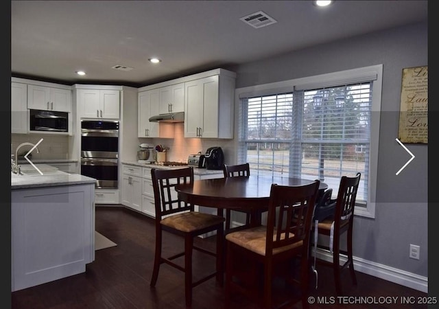 610 W Delaware St, Tahlequah, OK 74464 - kitchen with stainless steel double oven, under cabinet range hood, tasteful backsplash, white cabinetry, and recessed lighting