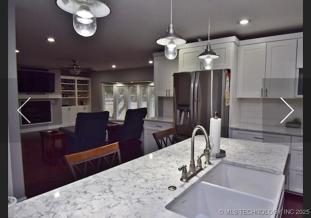 610 W Delaware St, Tahlequah, OK 74464 - kitchen with stainless steel fridge, a ceiling fan, white cabinets, pendant lighting, and light stone counters