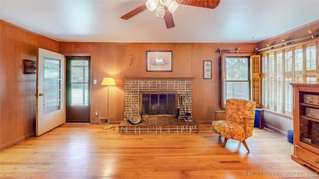 4040 E 46th Pl, Tulsa, OK 74135 - living room with a tiled fireplace, a ceiling fan, wood finished floors, crown molding, and wooden walls