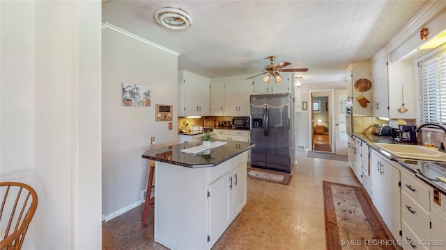 4040 E 46th Pl, Tulsa, OK 74135 - kitchen with appliances with stainless steel finishes, backsplash, white cabinetry, and a kitchen island