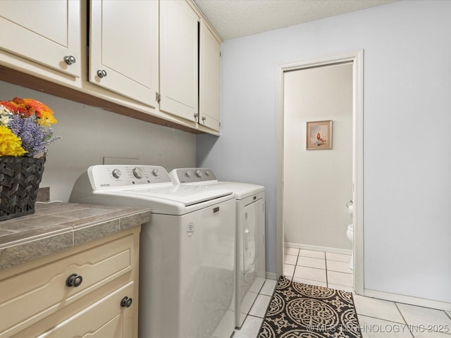 1726 Harned Dr, Bartlesville, OK 74006 - laundry room featuring washing machine and clothes dryer, cabinet space, light tile patterned flooring, and a textured ceiling