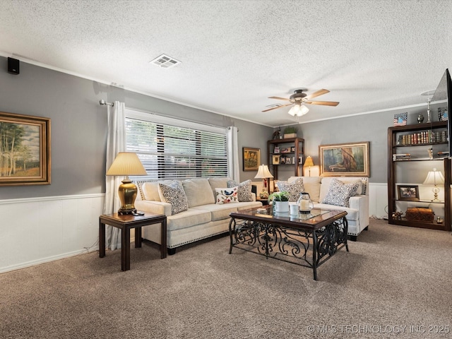 1726 Harned Dr, Bartlesville, OK 74006 - carpeted living room with a ceiling fan, a textured ceiling, a wainscoted wall, and crown molding