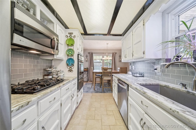 8736 E 59th St, Tulsa, OK 74145 - kitchen with stainless steel appliances, a warming drawer, white cabinets, backsplash, and stone tile flooring
