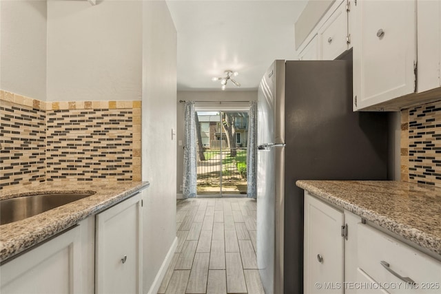 4660 E 68th St Unit 179, Tulsa, OK 74136 - kitchen featuring white cabinetry, freestanding refrigerator, backsplash, and light wood finished floors