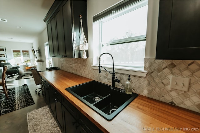 348550 E Parkside Dr, Pawnee, OK 74058 - kitchen featuring wooden counters, decorative backsplash, dark cabinetry, concrete floors, and open floor plan