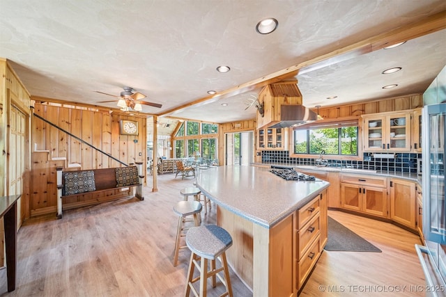 69125 E 252nd Rd, Wyandotte, OK 74370 - kitchen featuring exhaust hood, light wood finished floors, a center island, a breakfast bar area, and glass insert cabinets
