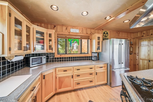 69125 E 252nd Rd, Wyandotte, OK 74370 - kitchen featuring stainless steel appliances, decorative backsplash, wooden walls, light wood-style flooring, and glass insert cabinets