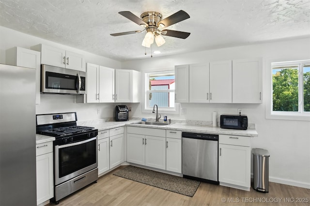 27719 S 610th Rd, Bunch, OK 74931 - kitchen featuring stainless steel appliances, light wood finished floors, white cabinets, ceiling fan, and a textured ceiling