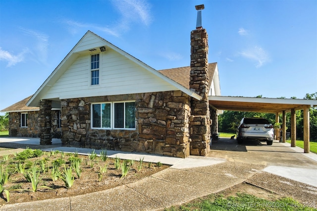 27719 S 610th Rd, Bunch, OK 74931 - view of front of house featuring stone siding, a chimney, concrete driveway, and an attached carport
